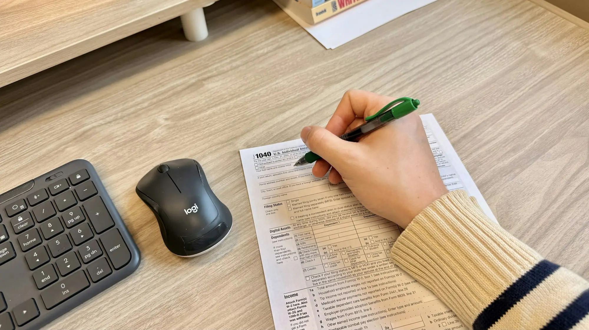 Business owner writing on paperwork next to a keyboard while reviewing a loan application