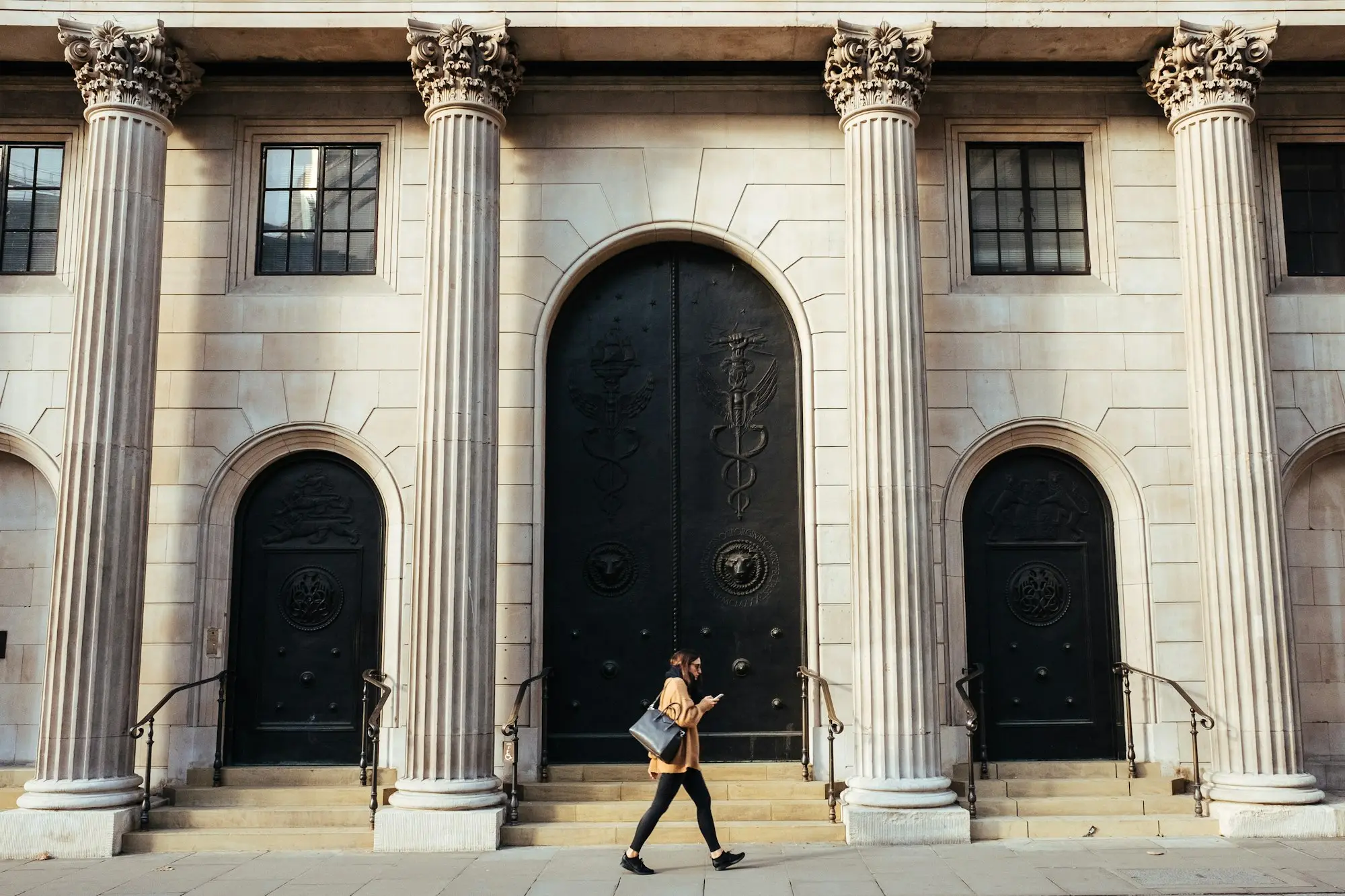 Woman walking past a white building with columns, weighing a bank against an alternative lender