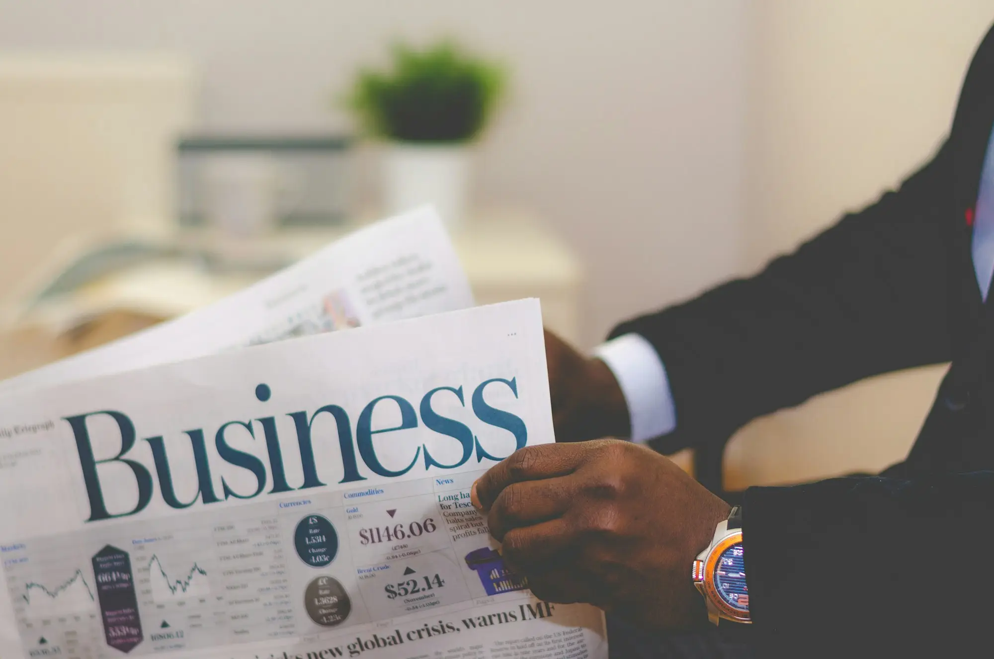 Business owner in a suit reading the business pages while weighing up lenders