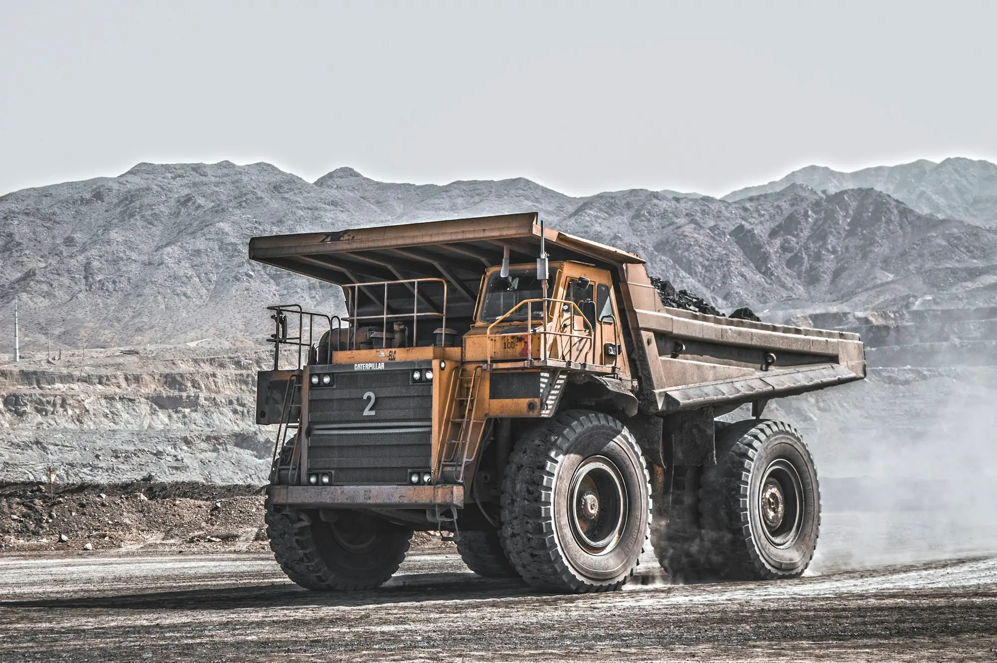 Haul truck on a dusty outback road near rocky ranges, a regional mining services business