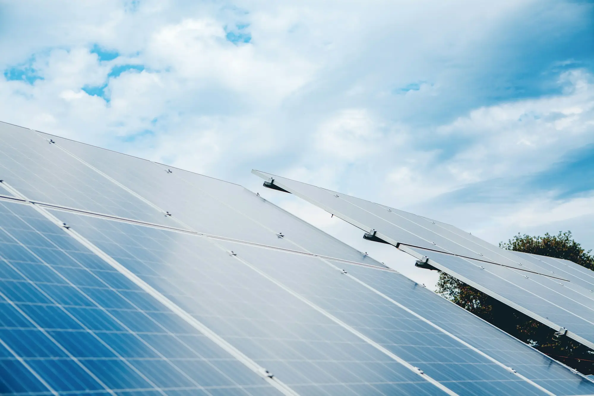 Rows of solar panels under a cloudy sky on a commercial solar installation