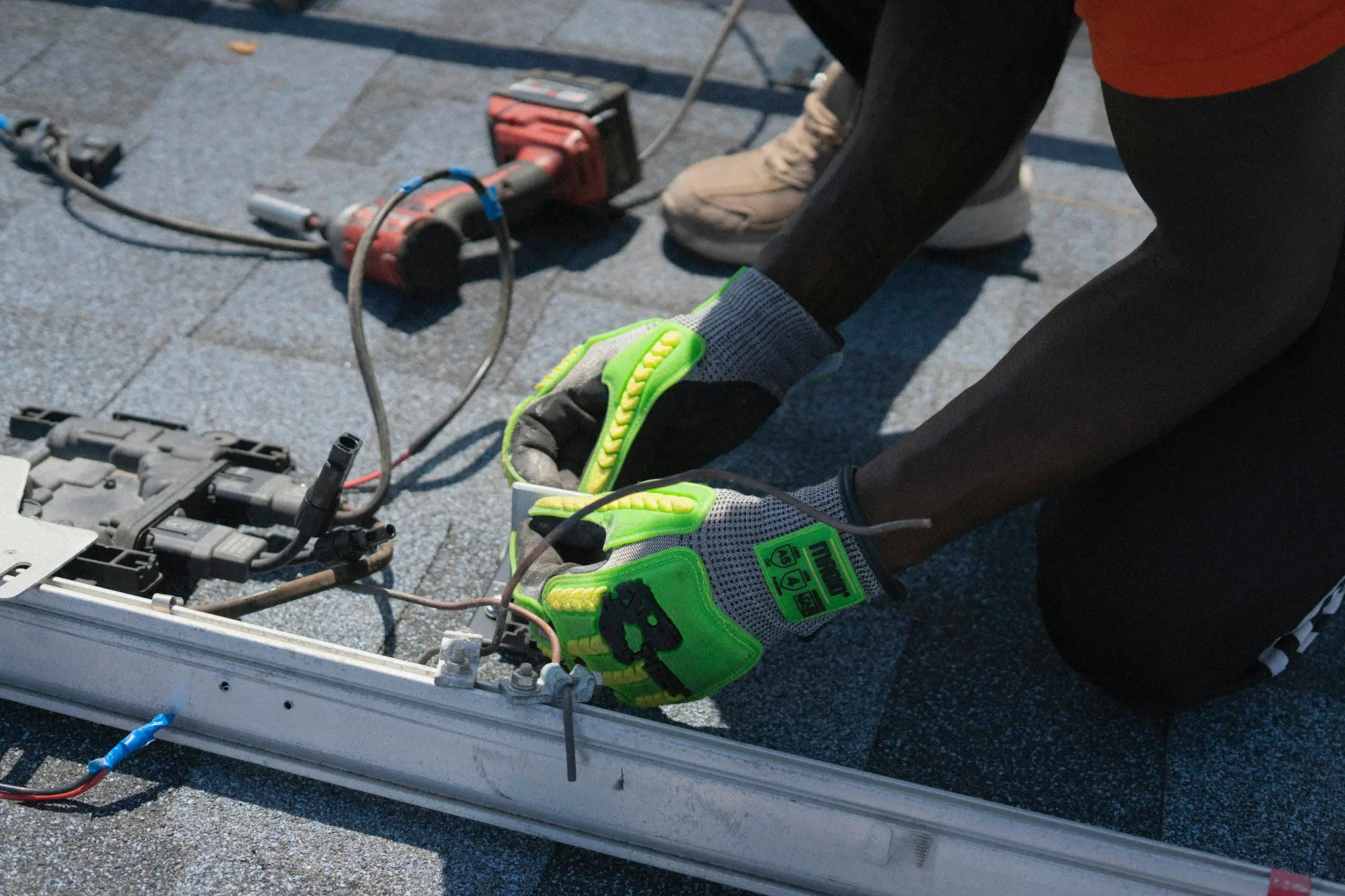Solar installer fitting electrical components on a roof during an installation job