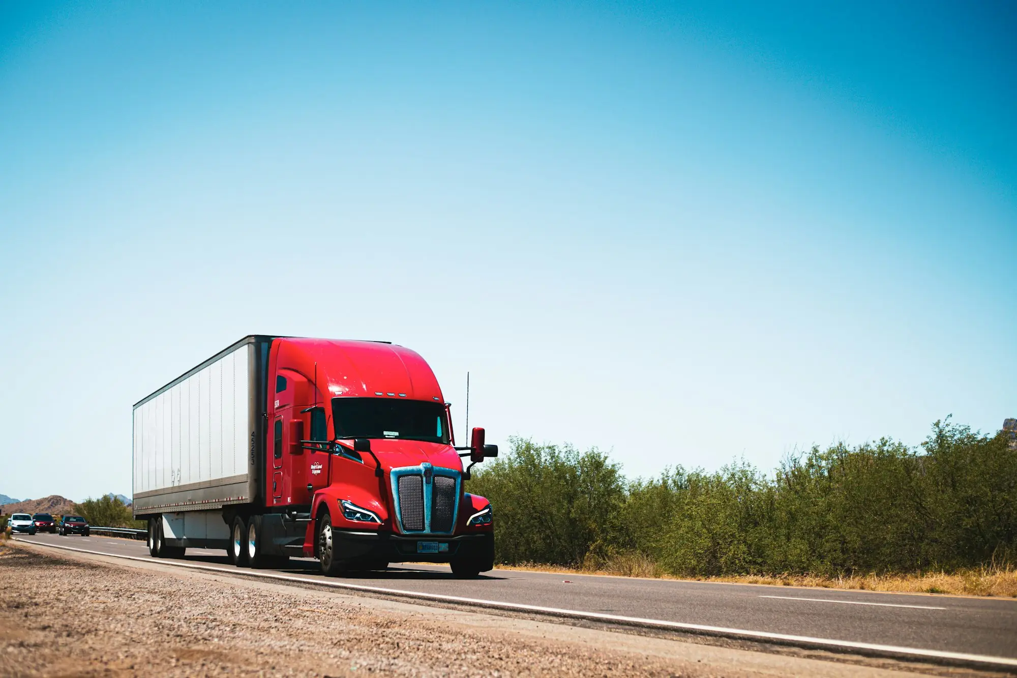 Red prime mover driving down a country road on a freight run